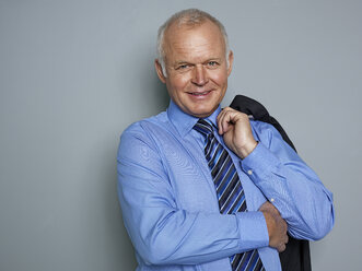 Portrait of businessman holding suit, smiling - STKF000203