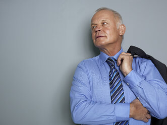 Businessman holding suit and looking away - STKF000204