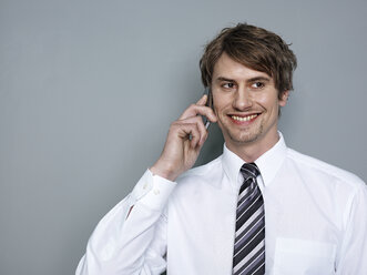 Geschäftsmann, der lächelnd mit einem Mobiltelefon spricht - STKF000213