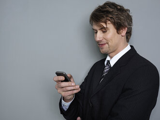 Businessman holding mobile phone, smiling - STKF000222