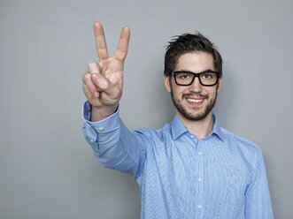 Businessman doing peace sign, smiling - STKF000228