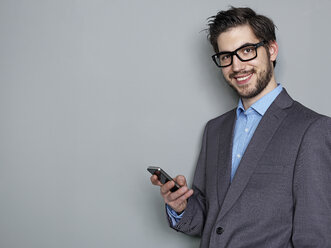 Portrait of businessman holding mobile phone, smiling - STKF000232