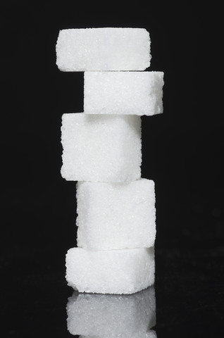 Stapel von Zuckerwürfeln auf schwarzem Hintergrund, lizenzfreies Stockfoto