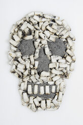 Skull shaped of cigarette stubs on white background - MUF001269