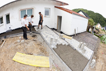 Deutschland, Rheinland-Pfalz, Arbeiter beim Zusammenbau von Pflastersteinen - CSF018065