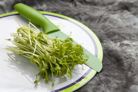 Erbsen grüne Ranken auf Teller mit Messer, Nahaufnahme, lizenzfreies Stockfoto