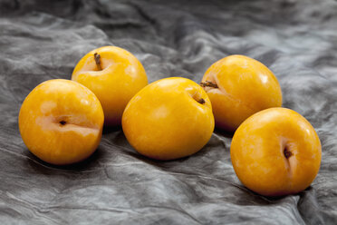 Yellow plums on grey background, close up - CSF018224