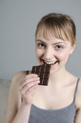 Porträt einer jungen Frau, die lächelnd Schokolade isst - ONF000067