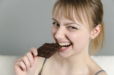 Porträt einer jungen Frau, die lächelnd Schokolade isst - ONF000068