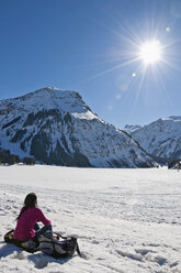 Österreich, Frau sitzt im Schnee in den Tannheimer Alpen - UMF000621