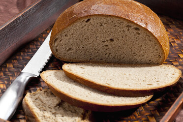Rustic rye mix bread with knife in tray, close up - CSF018325