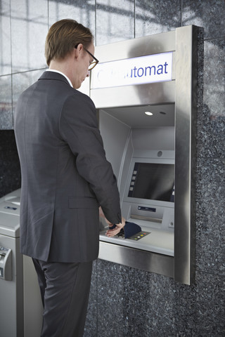 Deutschland, Köln, Älterer Mann am Geldautomaten im Flughafen, lizenzfreies Stockfoto