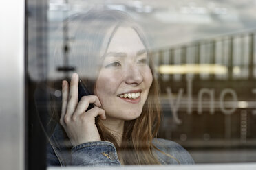 Germany, Cologne, Teenage girl talking on phone, smiling - RHYF000307