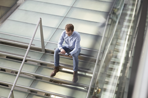 Germany, Cologne, Mid adult man using tablet at airport stock photo