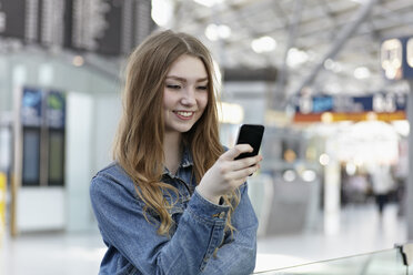 Deutschland, Köln, Jugendliches Mädchen hält Handy am Flughafen - RHYF000352