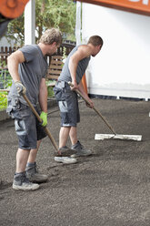 Germany, Rhineland Palatinate, Young men smoothing sand - CSF018358