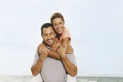 Spain, Mid adult man giving piggy back ride to woman, smiling - SKF001221