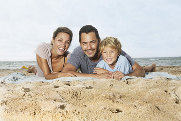 Spanien, Familie liegt am Strand von Palma de Mallorca, lächelnd - SKF001239