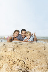 Spain, Family lying on beach at Palma de Mallorca, smiling - SKF001240