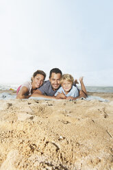 Spanien, Familie liegt am Strand von Palma de Mallorca, lächelnd - SKF001240