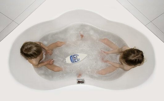 Austria, Boy and girl sitting in bathtube and playing with boat - CW000029