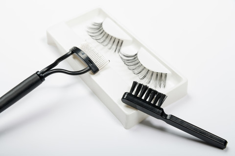 Falsche Wimpern, Wimpernkamm und Bürste auf weißem Hintergrund, Nahaufnahme, lizenzfreies Stockfoto