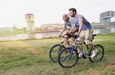 Germany, Cologne, Men riding bicycle - RHYF000365