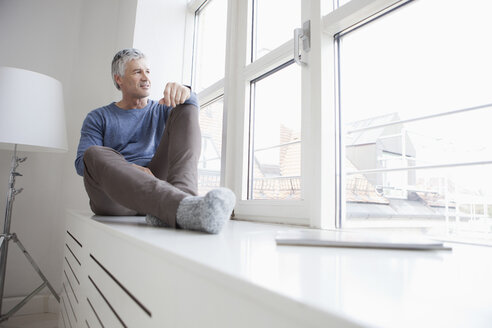 Deutschland, Bayern, München, Porträt eines reifen Mannes, der am Fenster sitzt und wegschaut - RBF001219