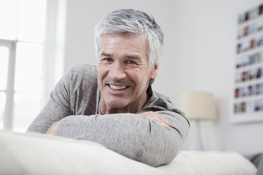 Germany, Bavaria, Munich, Portrait of mature man sitting on couch, smiling - RBF001234