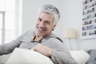 Germany, Bavaria, Munich, Portrait of mature man sitting on couch, smiling - RBF001248