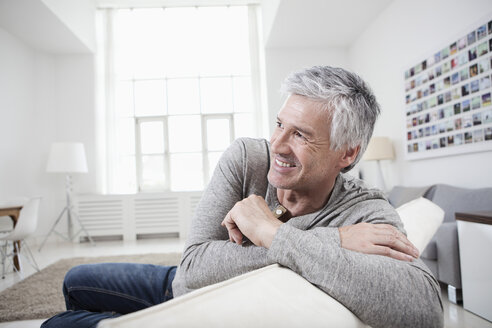 Deutschland, Bayern, München, Älterer Mann sitzt auf Couch, lächelnd - RBF001206