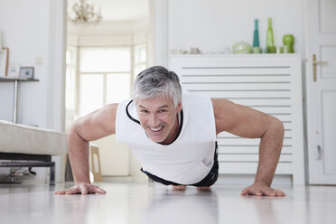 Germany, Bavaria, Munich, Mature man doing push ups at home, smiling - RBF001215