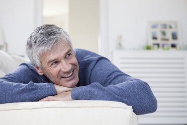 Deutschland, Bayern, München, Älterer Mann entspannt sich auf Couch, lächelnd - RBF001272