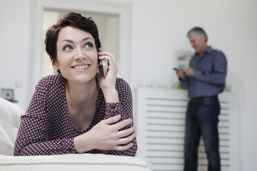 Germany, Bavaria, Munich, Woman talking on mobile phone while man in background - RBF001229