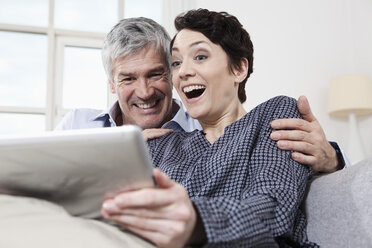 Germany, Bavaria, Munich, Couple using digital tablet at home, smiling - RBF001237
