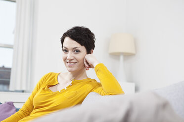 Germany, Bavaria, Munich, Portrait of mid adult woman sitting on couch, smiling - RBF001297