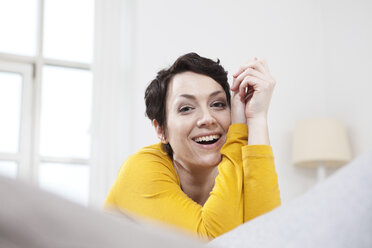 Germany, Bavaria, Munich, Mid adult woman sitting on couch, smiling - RBF001300