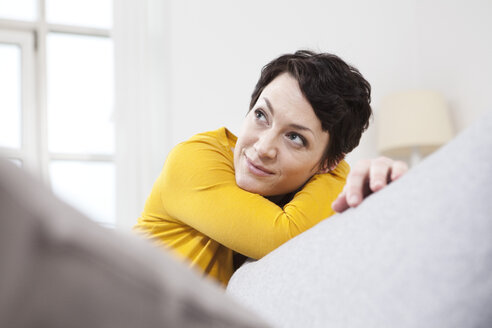 Deutschland, Bayern, München, Mid erwachsene Frau entspannt auf Couch, lächelnd - RBF001259