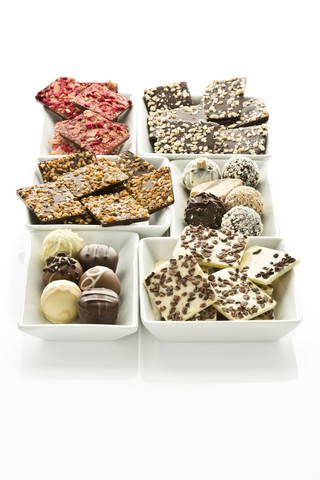 Verschiedene Schokoladen und Pralinen in Schalen auf weißem Hintergrund, lizenzfreies Stockfoto