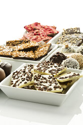 Verschiedene Schokoladen und Pralinen in Schalen auf weißem Hintergrund - MAEF006291