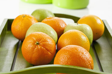 Green apples and oranges on wooden tray, close up - CSF018492