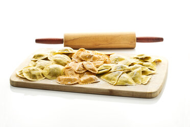 Variety of ravioli filled with tomato, ham and mushrooms on chopping board - MAEF006366