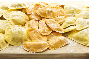 Variety of ravioli filled with tomato, ham and mushrooms on chopping board - MAEF006378