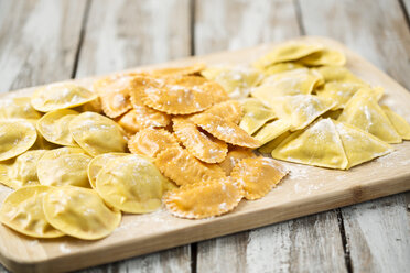 Variety of ravioli filled with tomato, ham and mushrooms on chopping board - MAEF006382