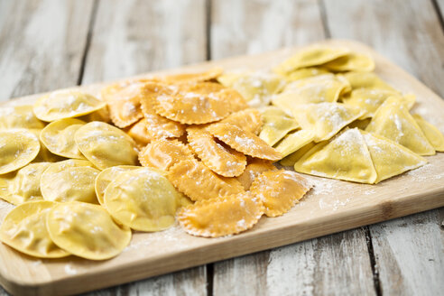 Verschiedene mit Tomaten, Schinken und Pilzen gefüllte Ravioli auf einem Schneidebrett - MAEF006382