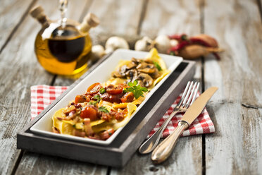 Verschiedene Ravioli gefüllt mit Tomaten, Schinken und Pilzen auf einem Teller - MAEF006422