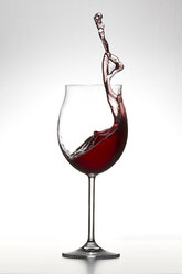 Rotwein spritzt im Glas auf weißem Hintergrund - PSAF000009