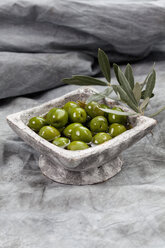 Schale mit grünen Oliven in Olivenöl auf Textil, Nahaufnahme - CSF018506