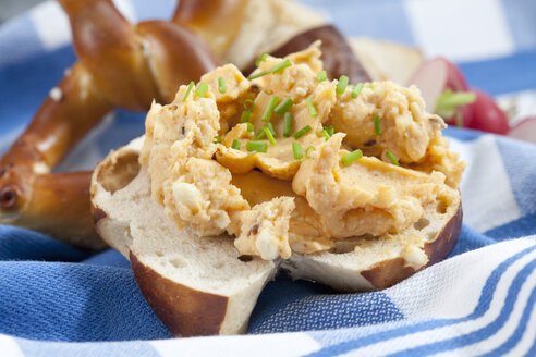 Laugenbrötchen mit Obatzda und Schnittlauch auf Serviette, Nahaufnahme - CSF018513