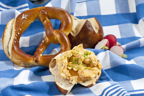 Laugenbrötchen mit Obatzda und Schnittlauch auf Serviette, Nahaufnahme - CSF018514